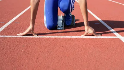 A runner waiting on a racing block for the starting sign.